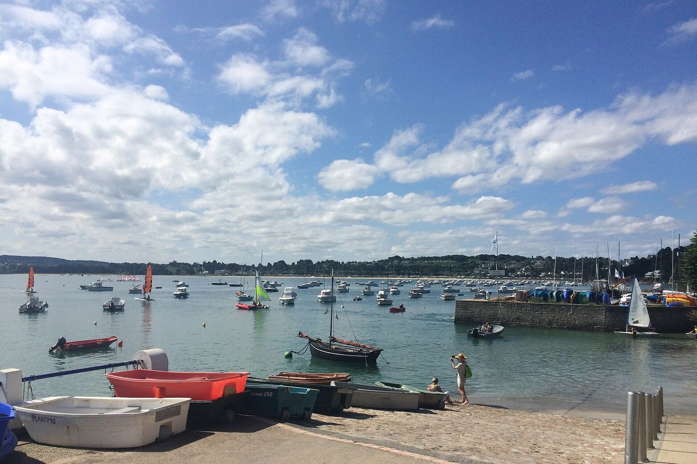 Le port de plaisance de Locquirec, voiliers au mouillage et barques sur le sable, sous un ciel de nuages