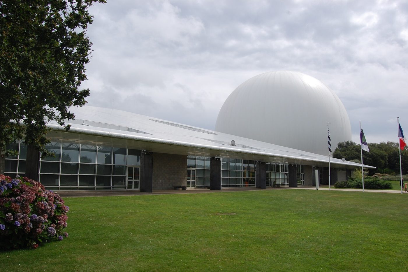 Le Radôme blanc et le bâtiment de la Cité des télécoms entourés de pelouse, à Pleumeur-Bodou
