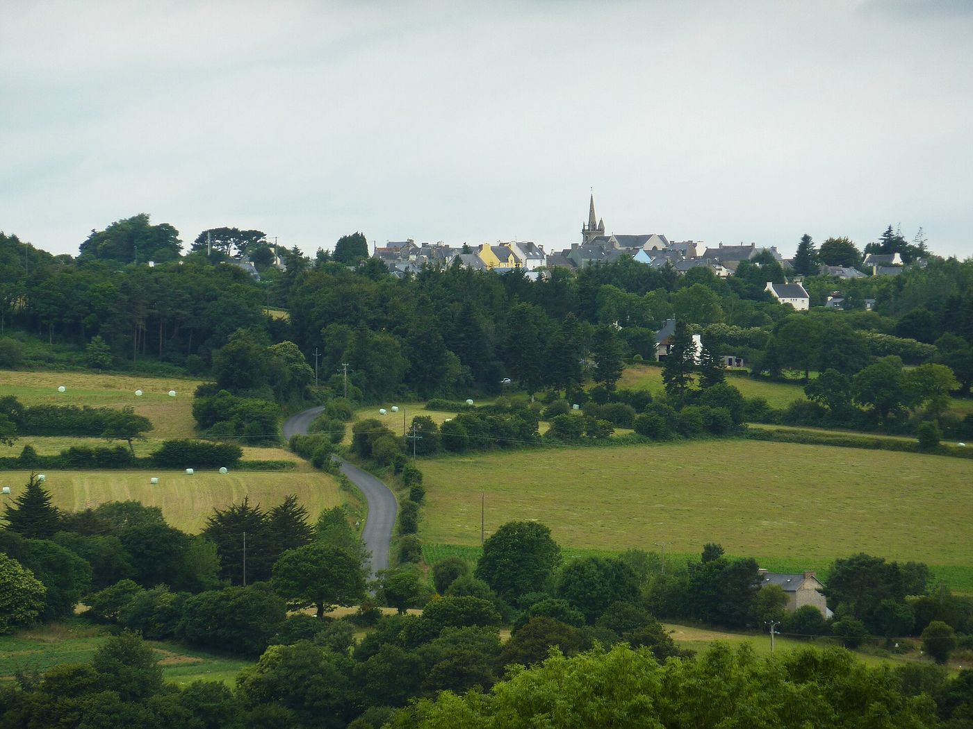 Le bourg de Scrignac perché sur sa colline, vu de loin à travers prairies et haies bocagères