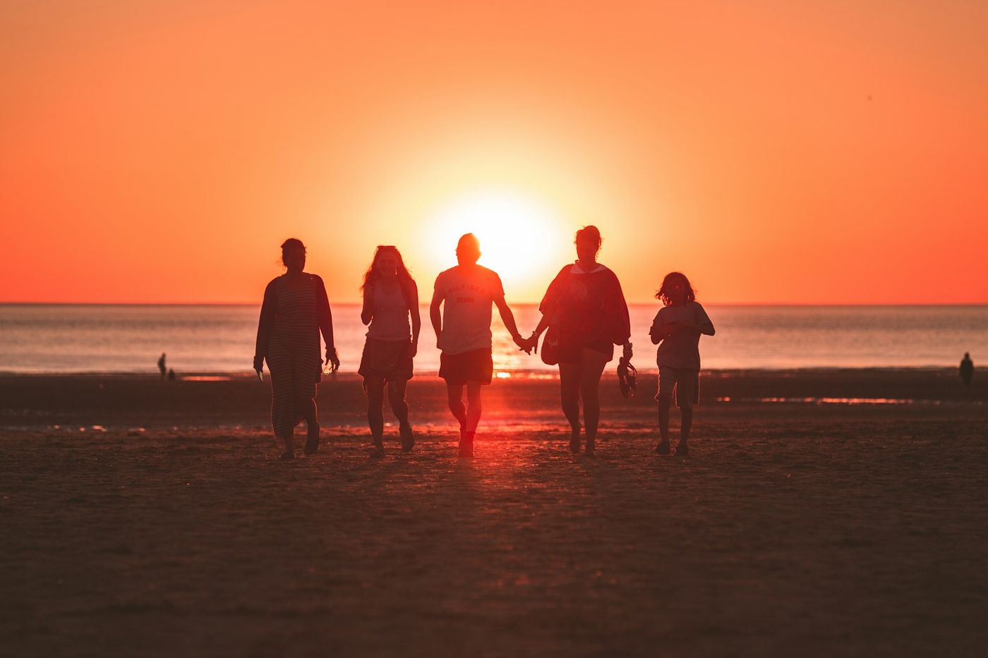 Une famille en silhouette, main dans la main face au soleil couchant, image de la transmission entre générations pour les habitants de Sizun