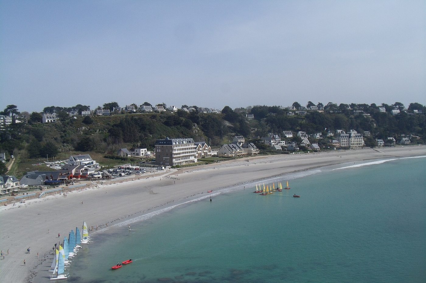 Plage de Tresmeur bordée de maisons et dériveurs sur l'eau turquoise, à Trébeurden